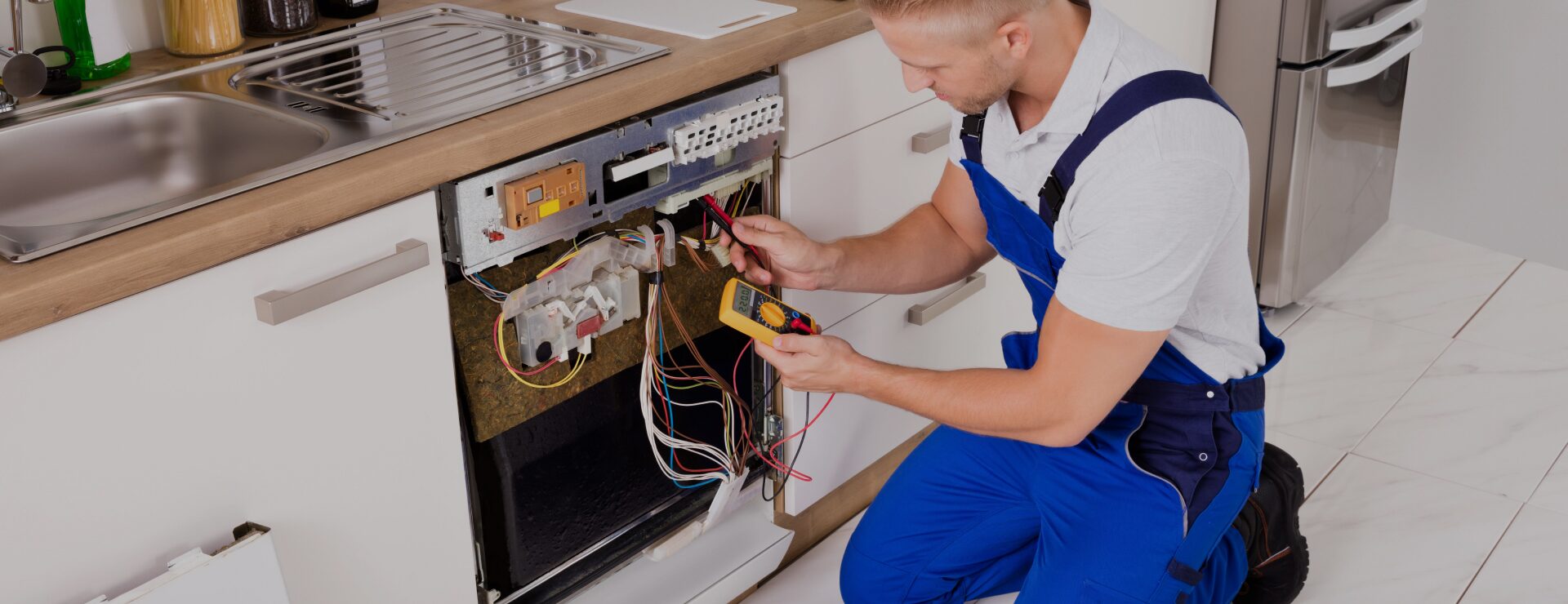 Aurus technician diagnosing a built-in dishwasher with a multimeter